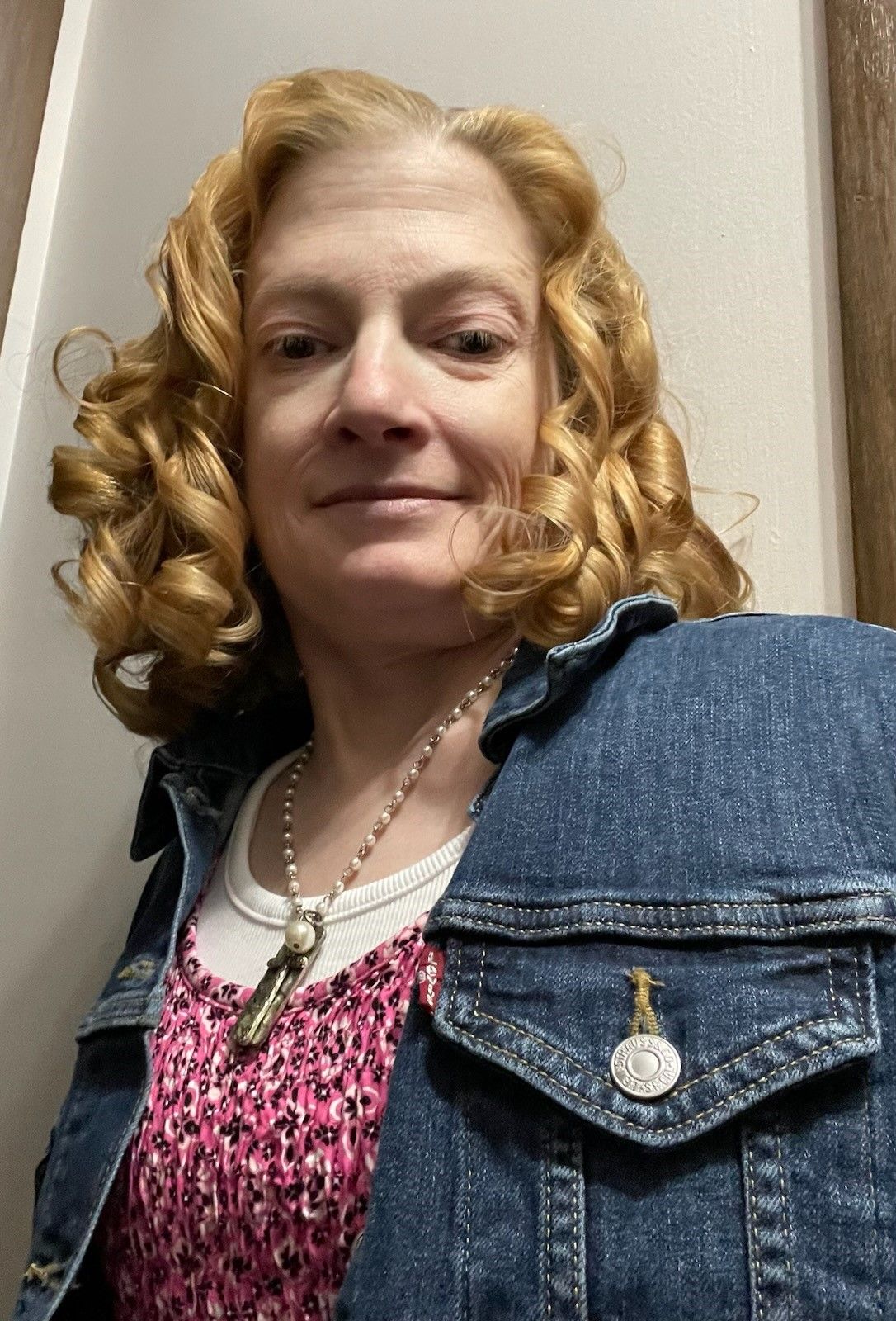 A woman with curly hair is wearing a denim jacket and a white shirt. This is Lori Tenaglia.
