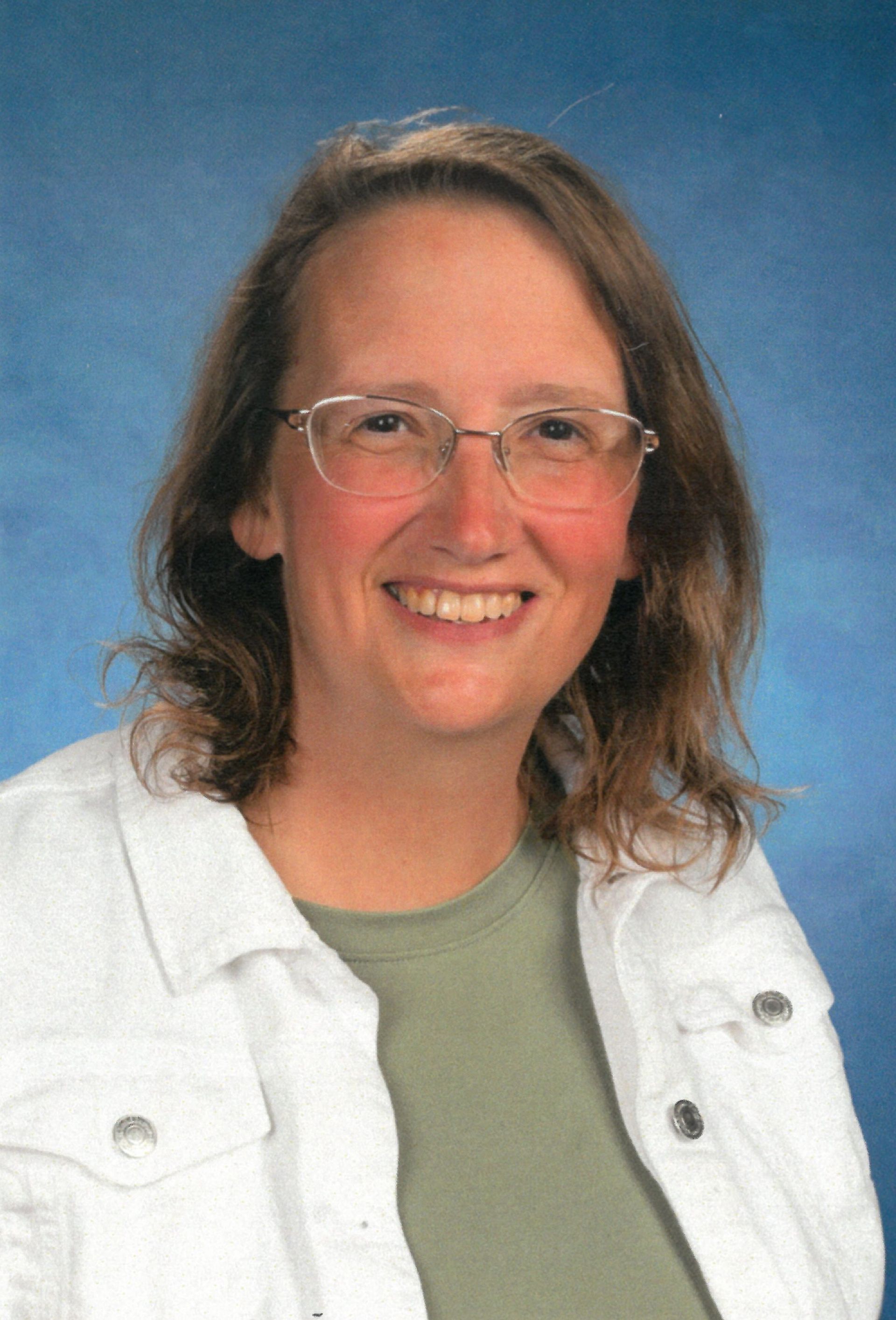 A woman wearing glasses and a white jacket is smiling for the camera. This is michelle Porter.