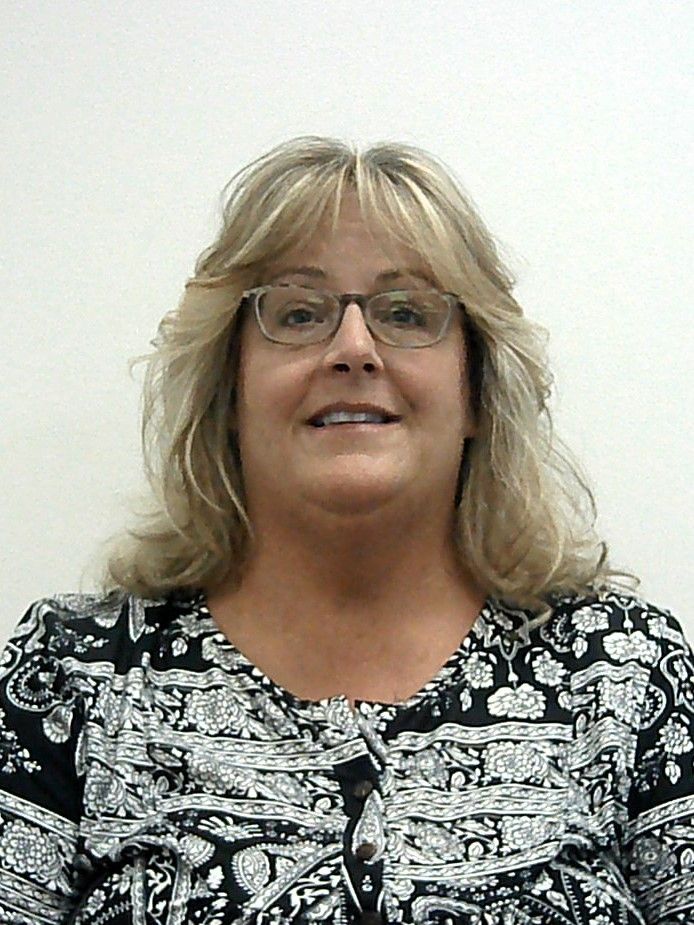 A woman wearing glasses and a black and white shirt is smiling for the camera.