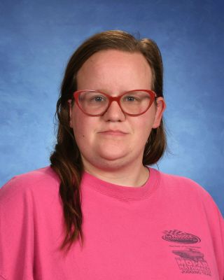 A woman wearing glasses and a pink shirt is posing for a picture.