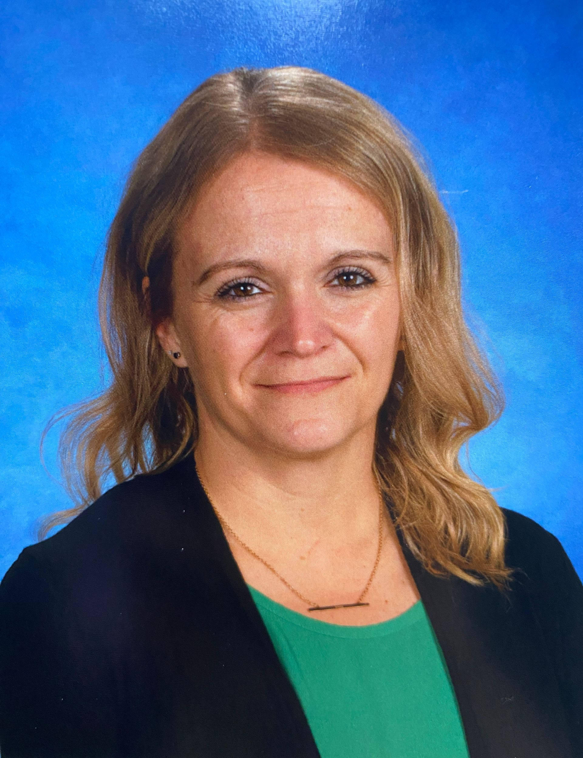 A woman in a black and yellow floral shirt is smiling for the camera.
