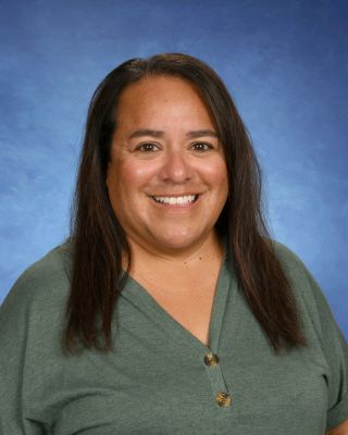 A woman in a green shirt is smiling for a picture.