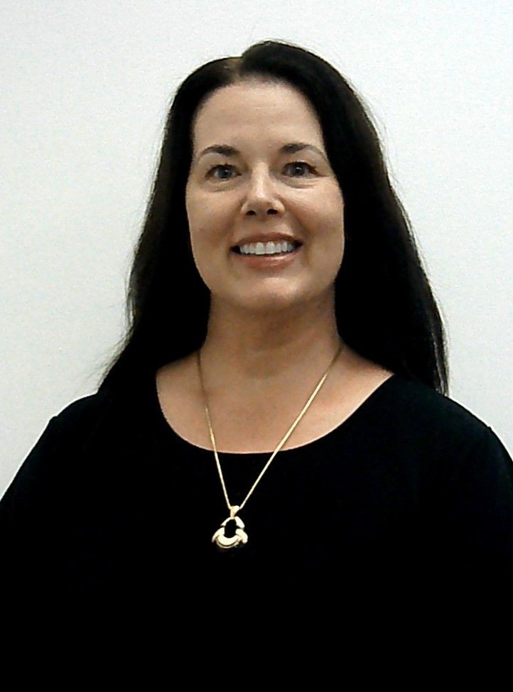 A woman wearing a black shirt and a gold necklace smiles for the camera