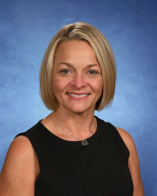 A woman wearing glasses and a sweater is smiling for a picture. This is Marty Sheets.