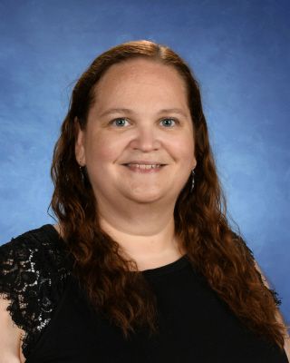 A woman wearing a black shirt and a gold necklace smiles for the camera