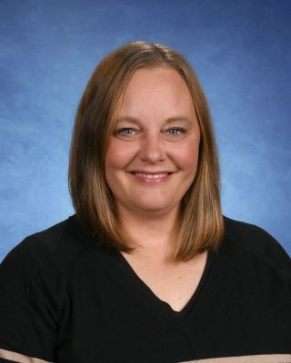 A woman in a red floral shirt is smiling for the camera.