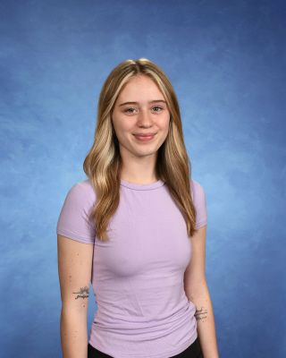 A woman wearing a floral shirt is smiling for the camera