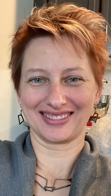 A woman with short red hair is smiling for the camera.