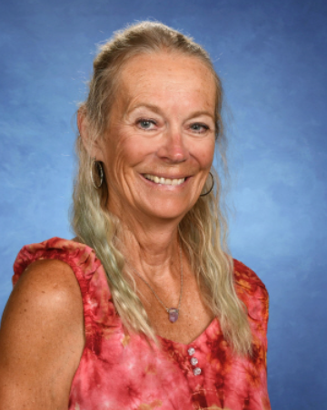 A woman wearing glasses and a black jacket is smiling for the camera.