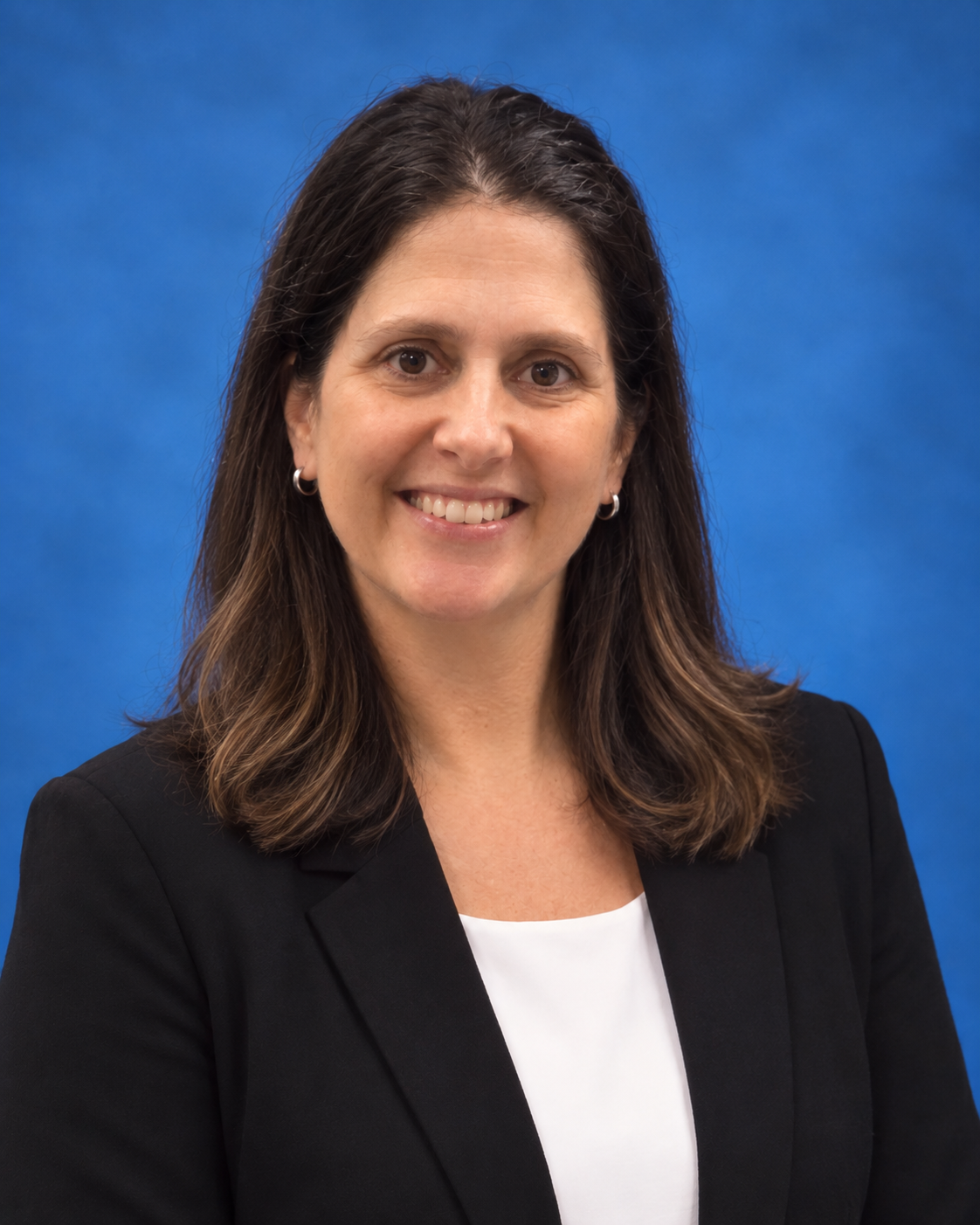 A woman in a red shirt is smiling in front of a blue background.This is Megan Miller.