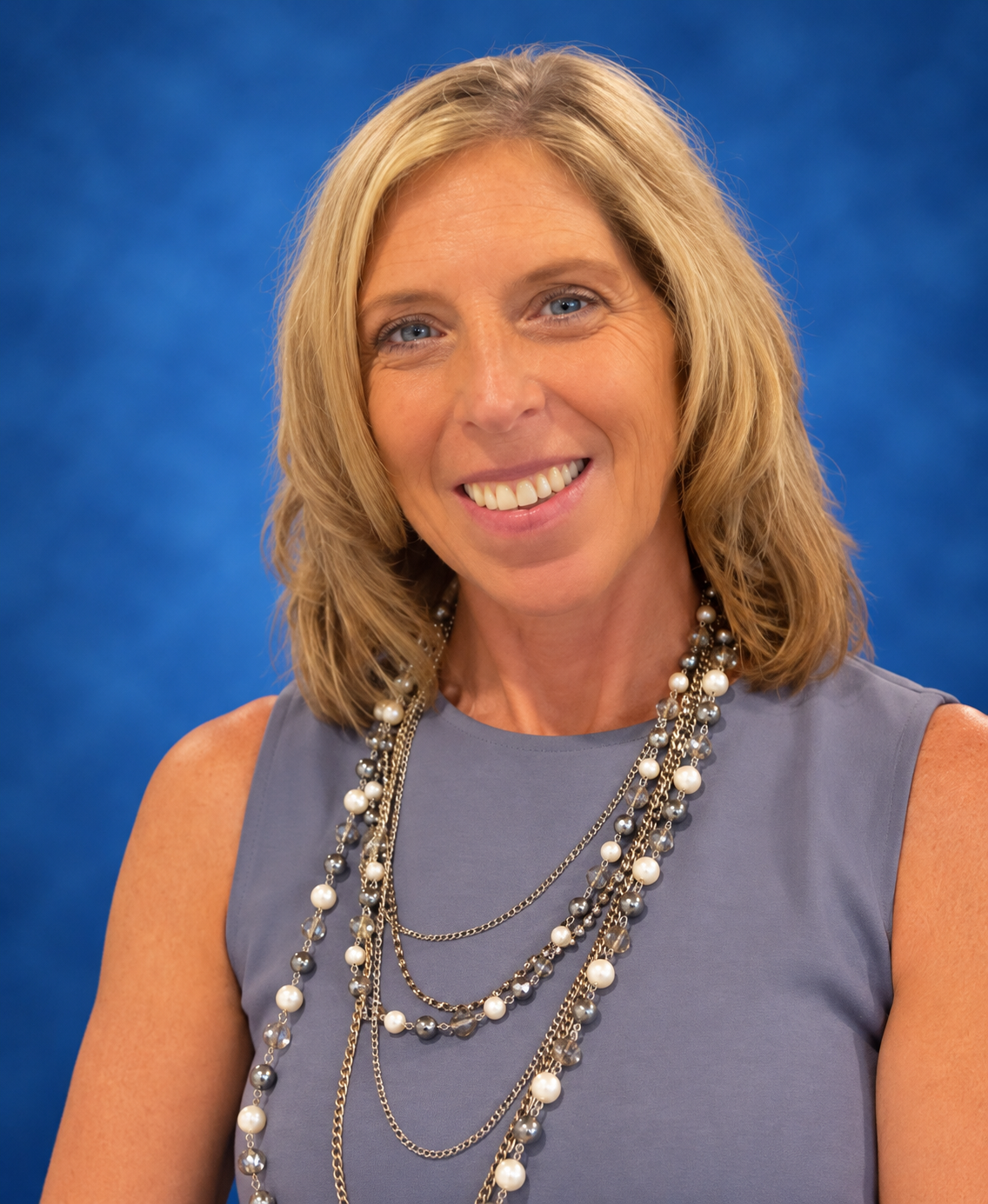 A woman in a brown shirt is smiling for the camera.