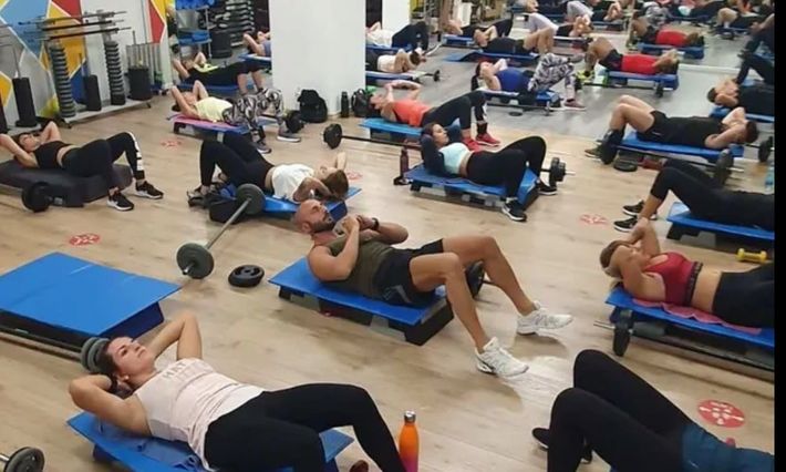 Persone che si allenano su dei tappetini in una palestra.