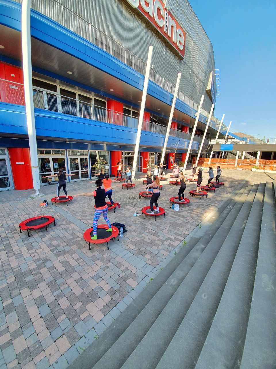Persone che si allenano con i cerchi all'esterno di un grande stadio con dettagli rossi e blu.