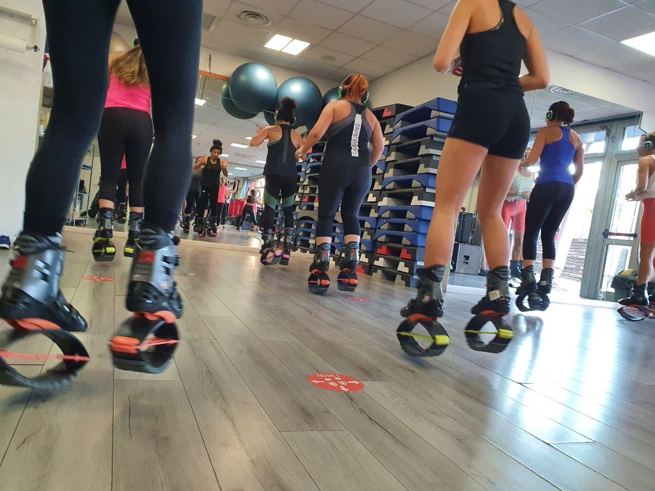Lezione di fitness di gruppo con persone che saltano su stivali a molla in una sala fitness.