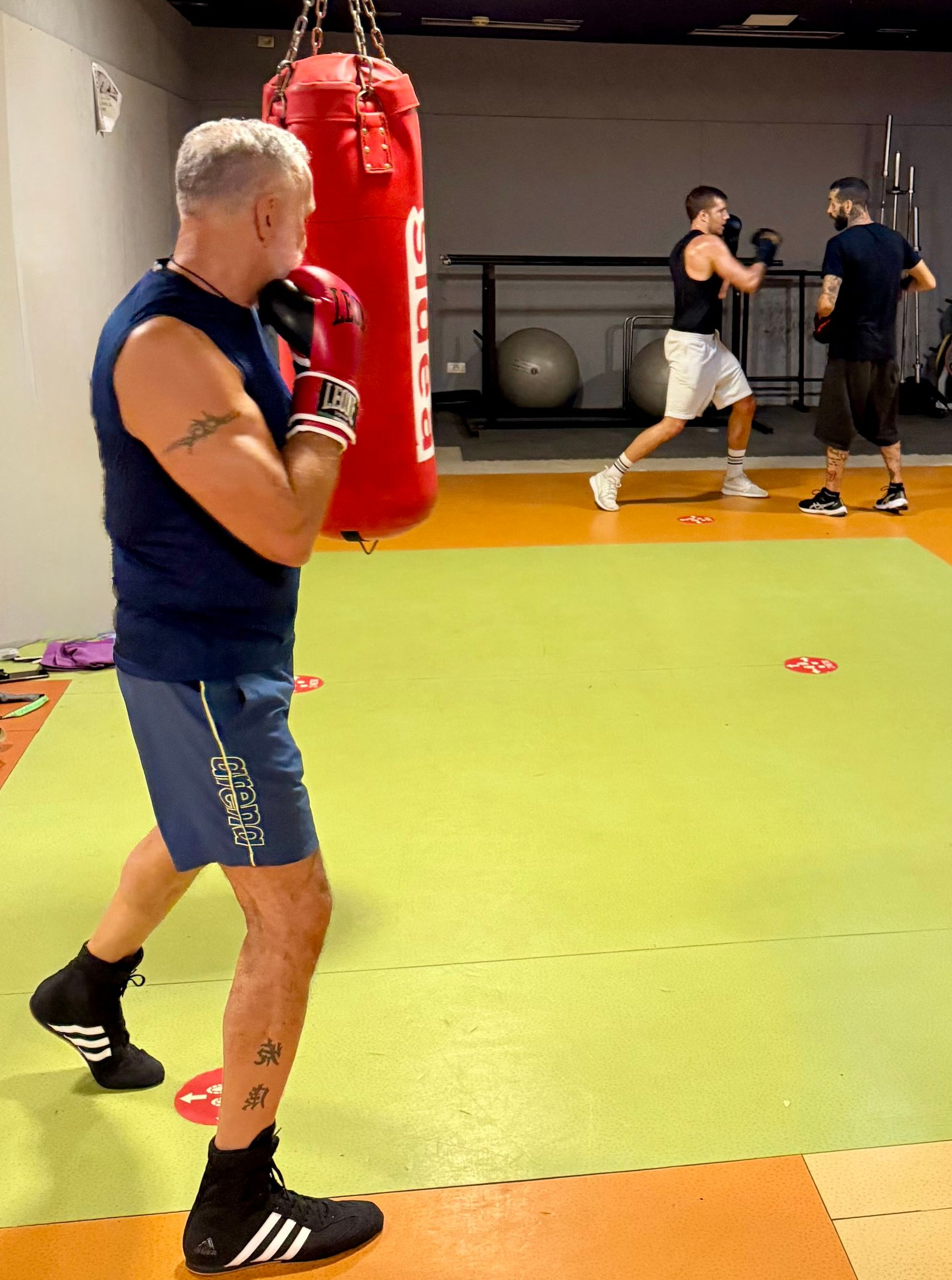 Palestra di pugilato con un uomo che si allena vicino a un sacco da boxe rosso