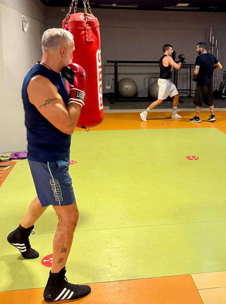 Palestra di pugilato con un uomo che si allena vicino a un sacco da boxe rosso