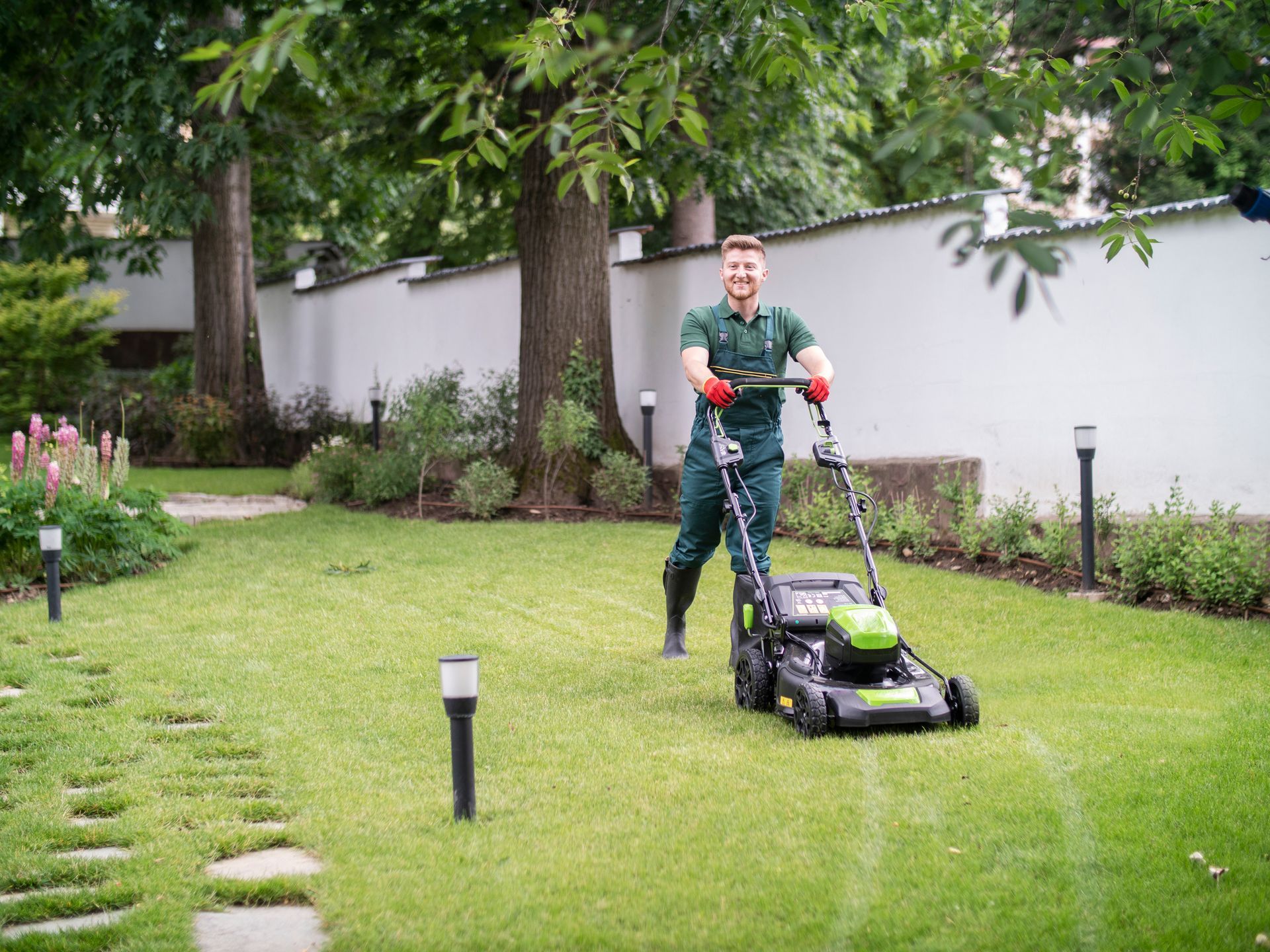 Full length gardener mows the lawn with a mower in beautiful garden | Morristown, NJ |