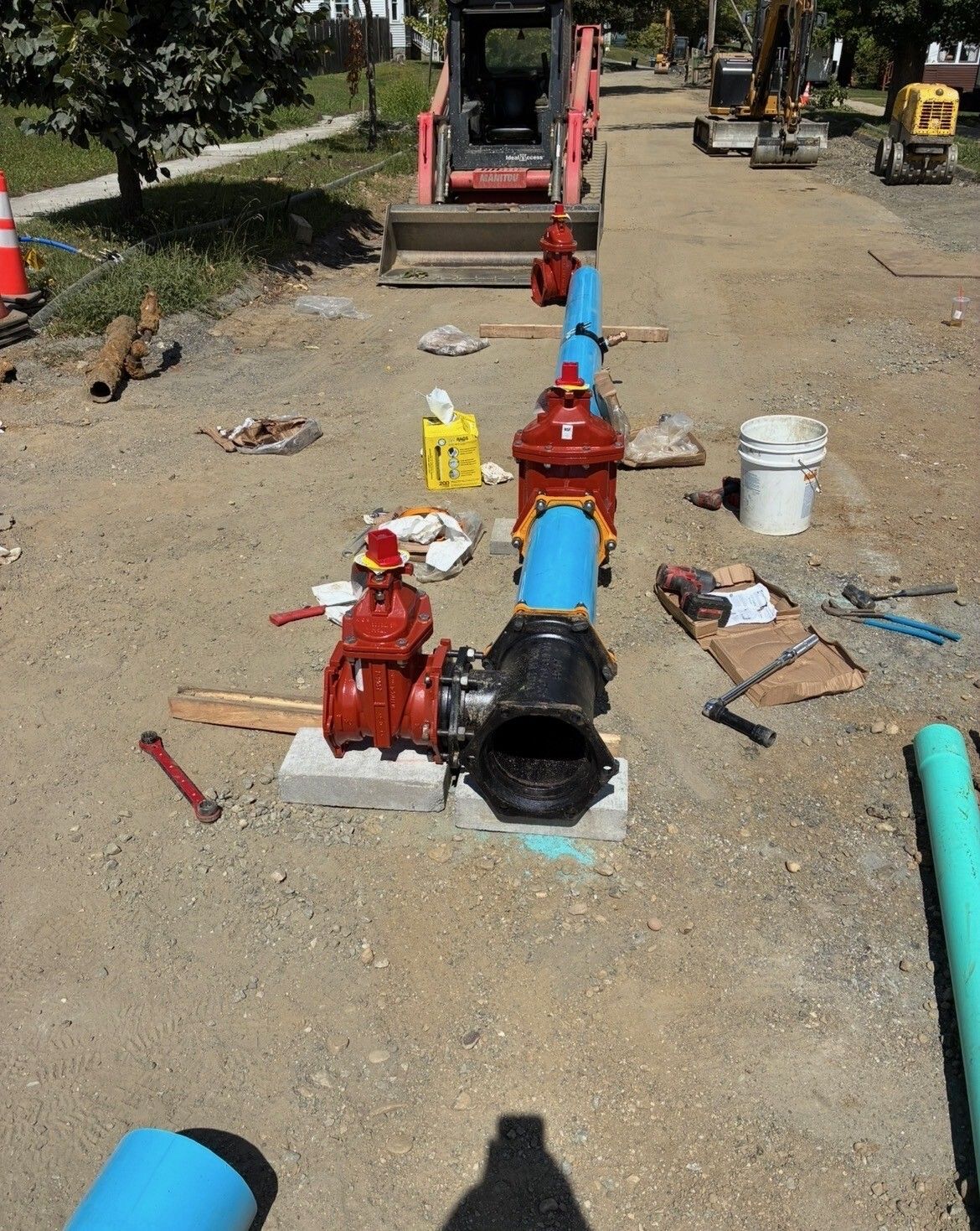 Red fire hydrant valves and blue pipes laid out on gravel at a construction site. Red fire hydrant valves and blue pipes laid out on gravel at a construction site.
