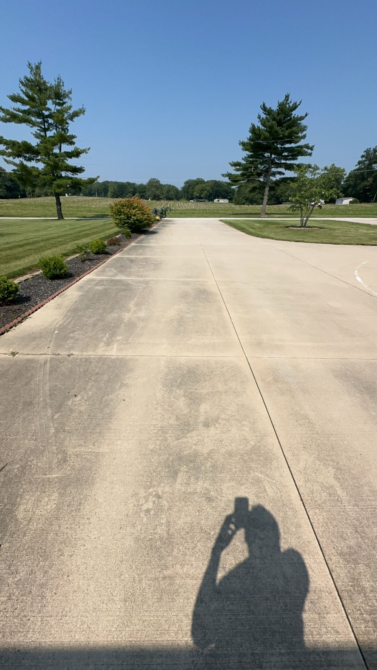 A person is taking a picture of their shadow on the sidewalk.