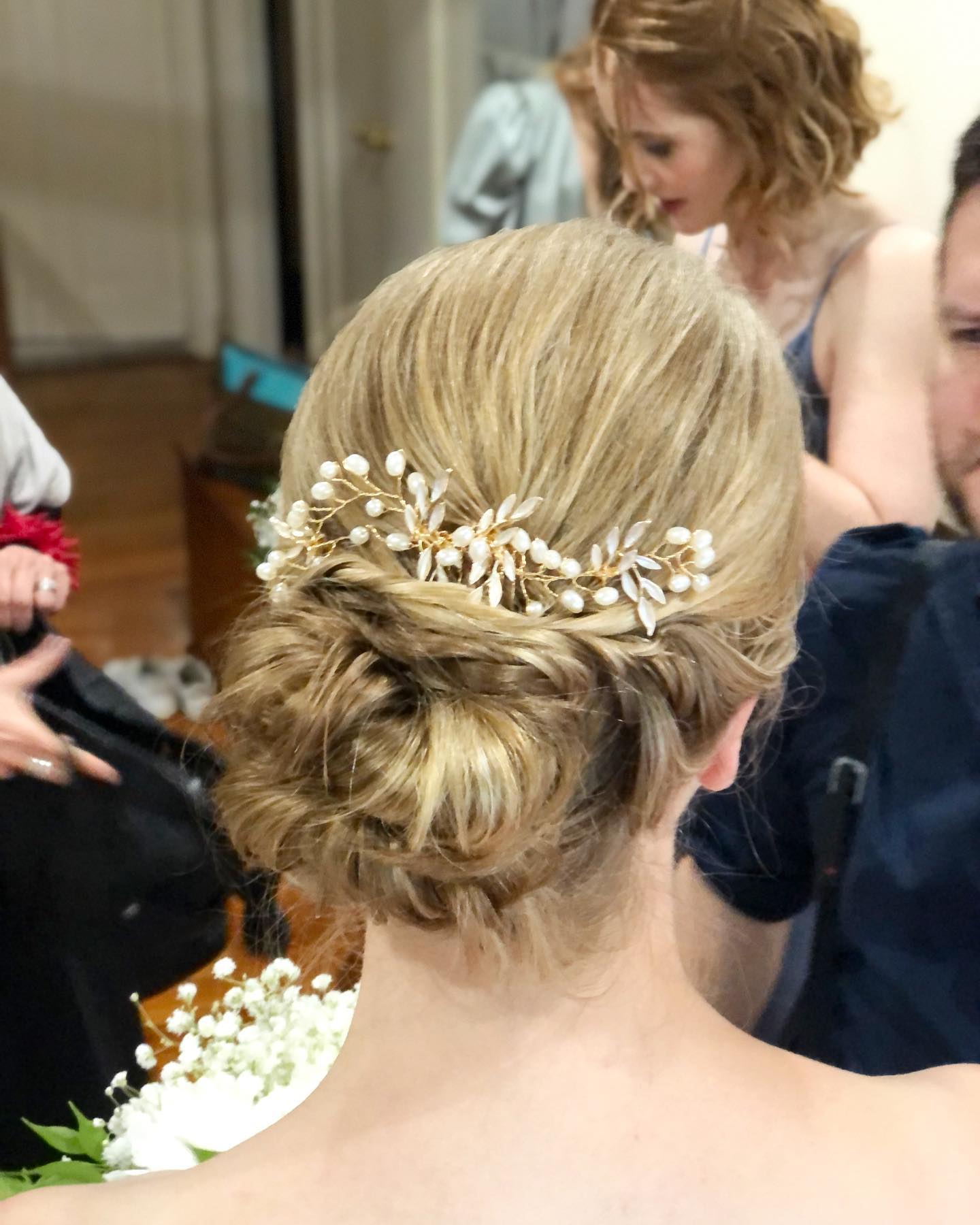 The back of a woman 's head with a bun and a flower in her hair.