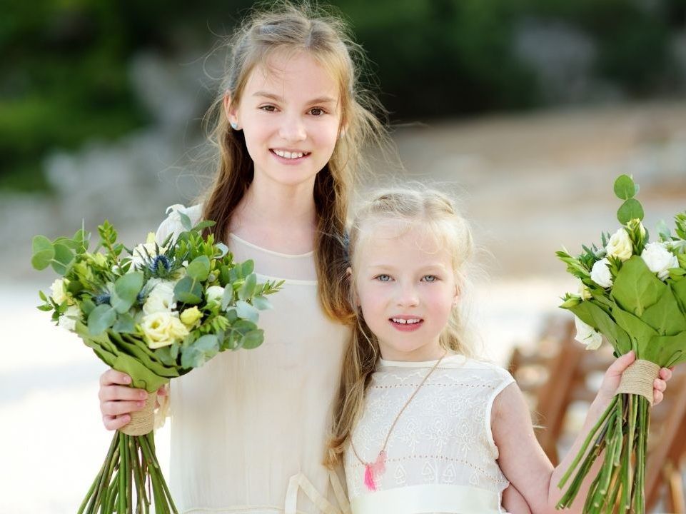 Two little girls are holding bouquets of flowers.