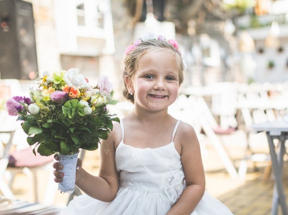 A little girl in a white dress is holding a bouquet of flowers.