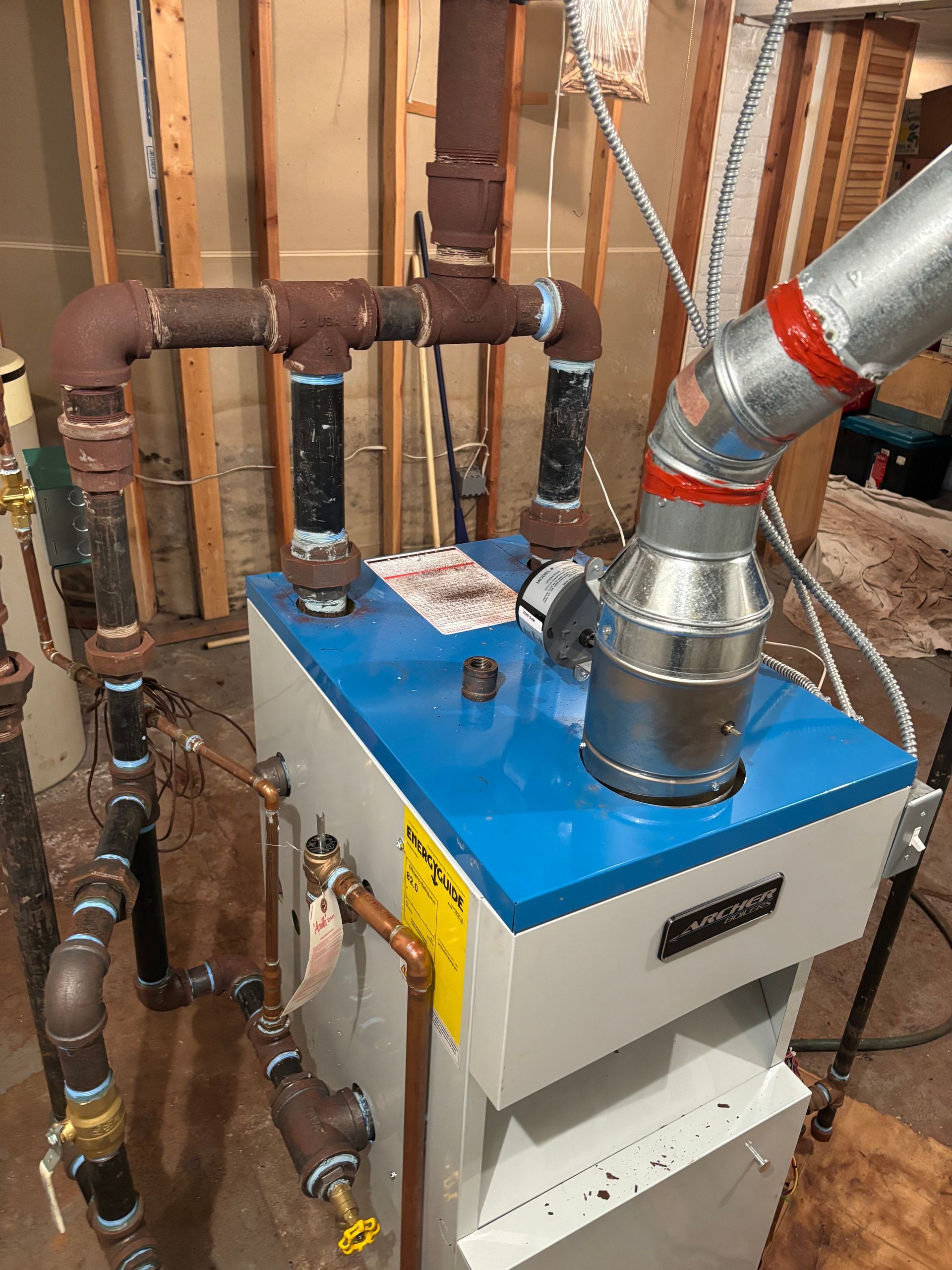 Blue boiler unit with silver ducting and copper pipes in a basement utility room