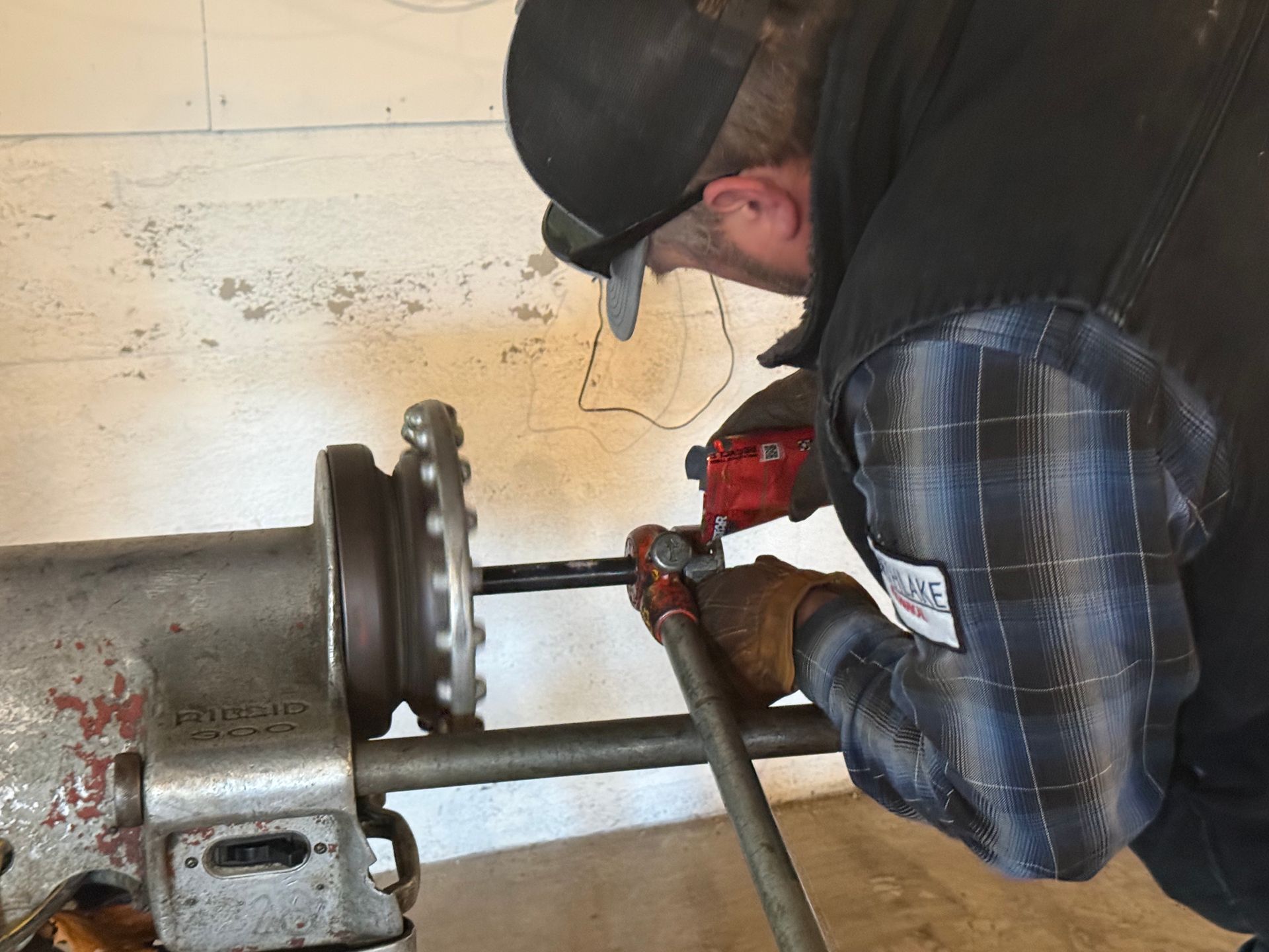 Worker using a red power tool to repair metal piping in an industrial setting