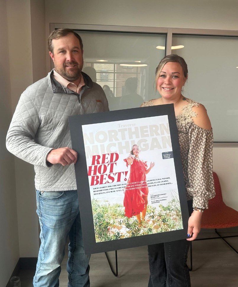Two people holding a framed Northern Red and Blue poster, standing indoors and smiling.