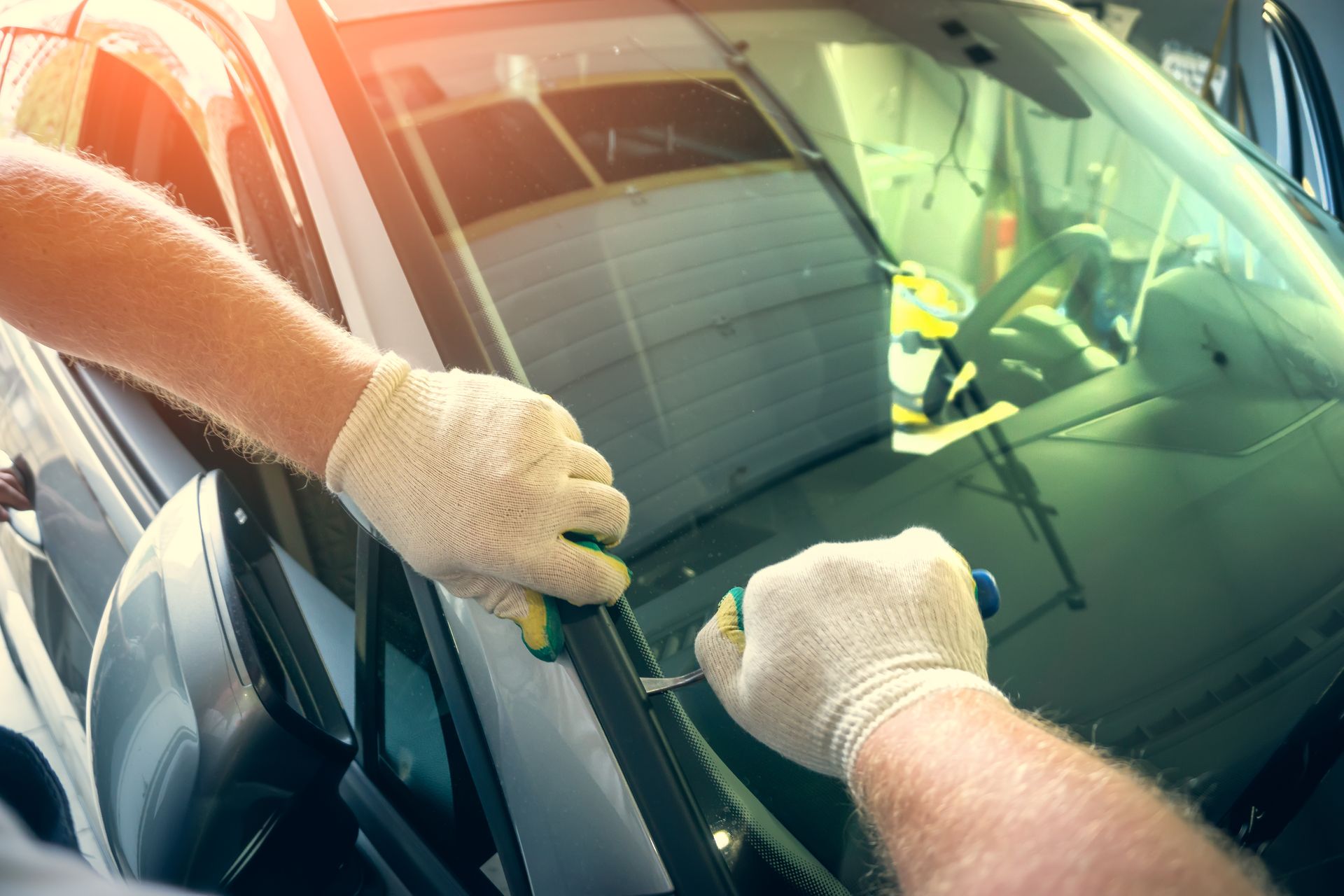 Service worker dismantle broken glass windscreen or windshield before installing new one on car in auto station garage. Service worker dismantle broken glass windscreen or windshield before installing new one on car in auto station garage.