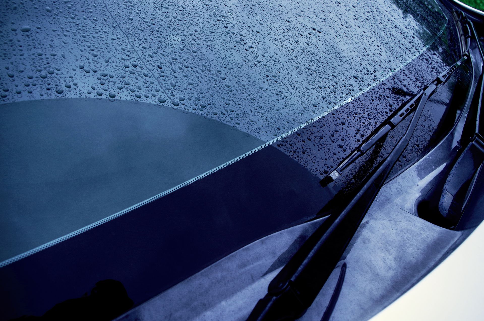 Close-up of a car windshield with rain droplets and wipers.
