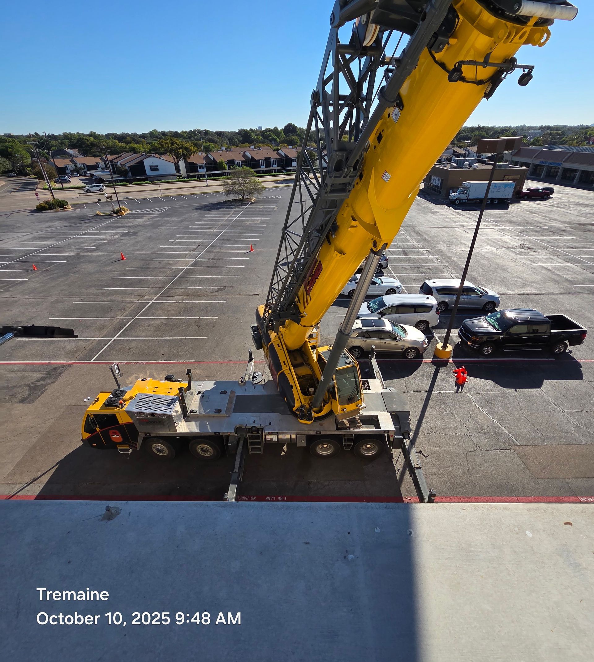 Yellow crane on a parking lot, lifting or assembling something. Sunny day.