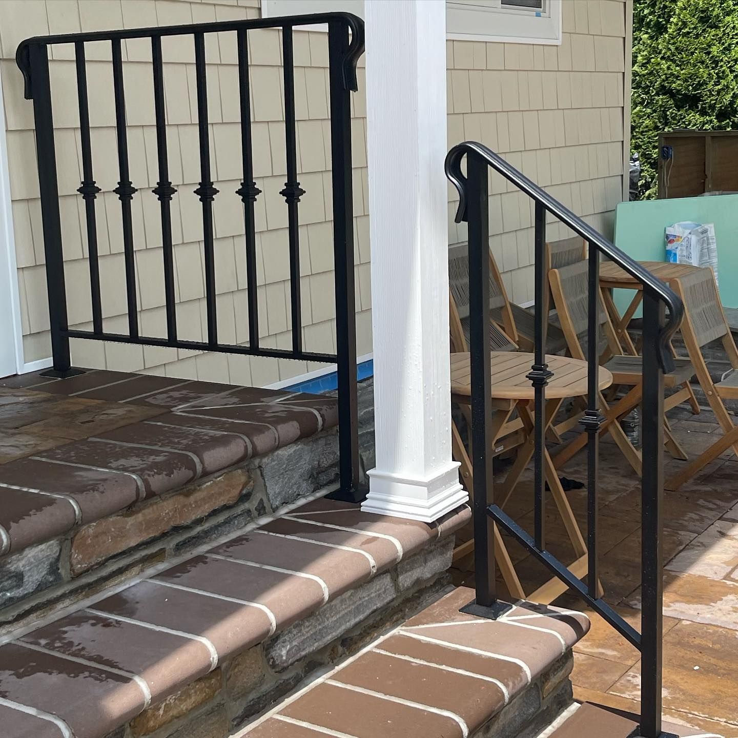 Black wrought-iron handrails installed on stone steps leading to a house entrance.