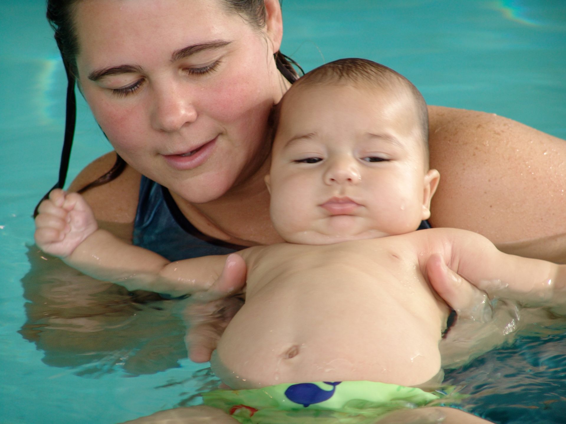 A woman is holding a baby in a swimming pool