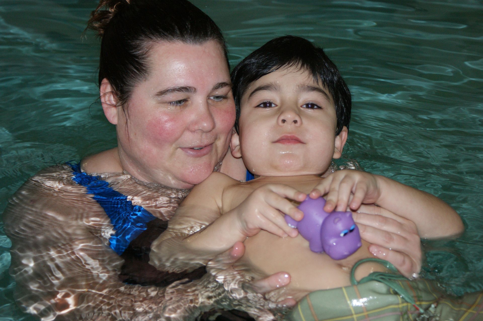 A woman is holding a child in a swimming pool.