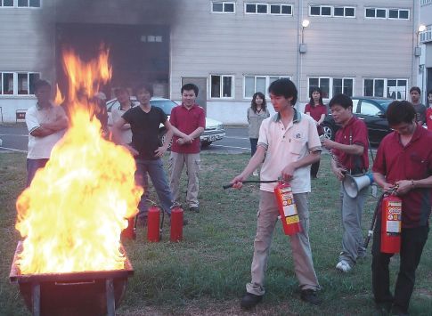 外勞生活協助中的消防安全培訓實況，移工學員在指導下實際操作滅火器撲滅火焰。