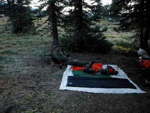 A man is laying on a blanket in the woods.
