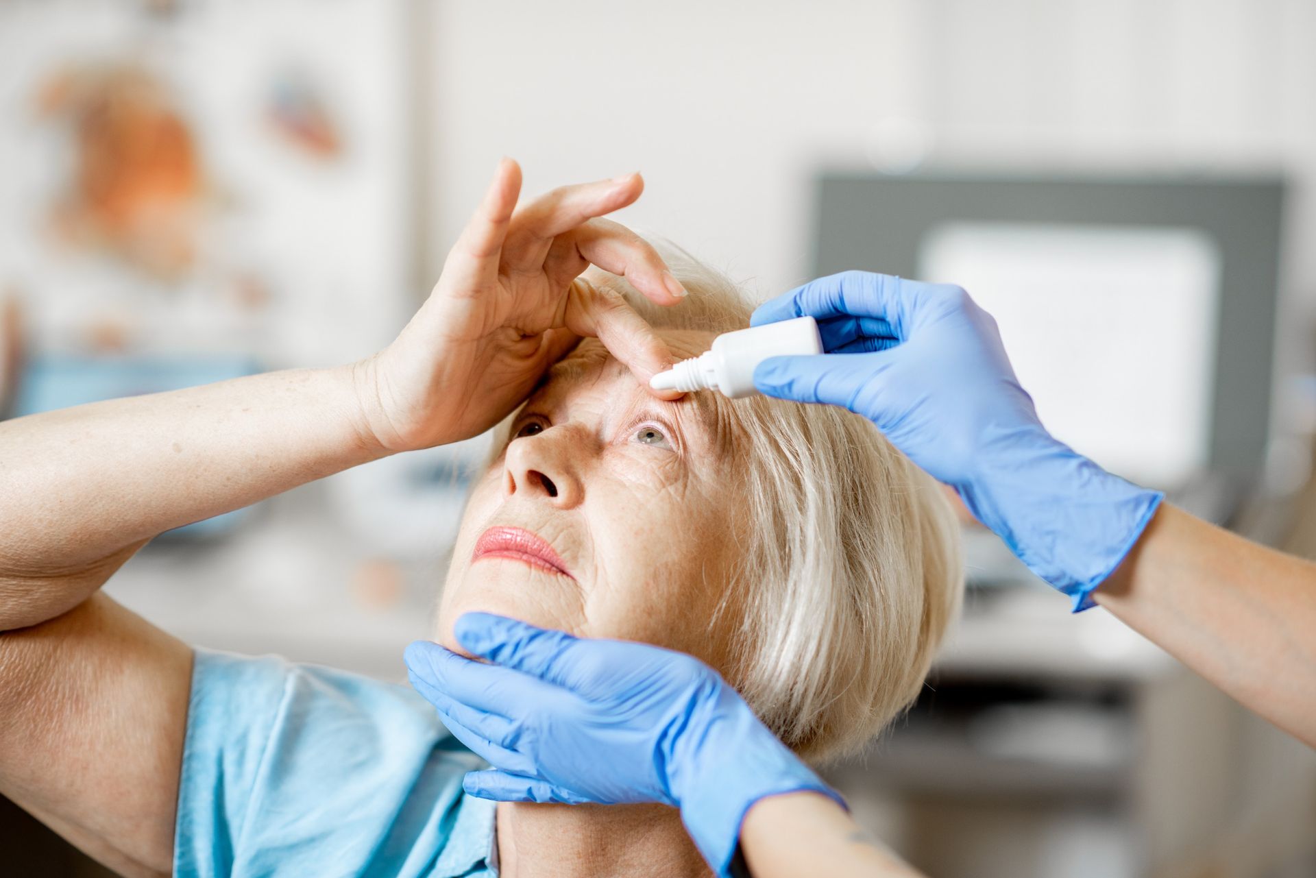 An elderly woman is getting her eyes examined by a doctor.