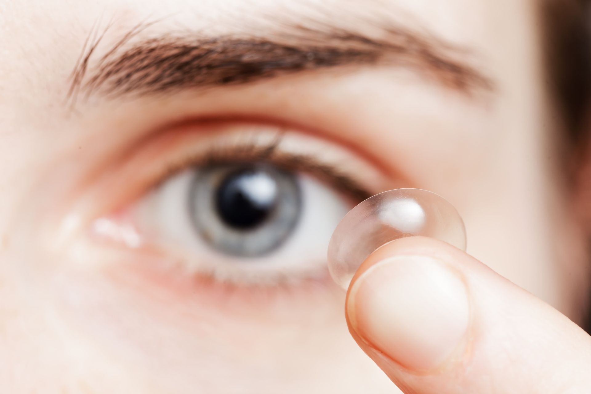 A person is putting a contact lens in their eye.
