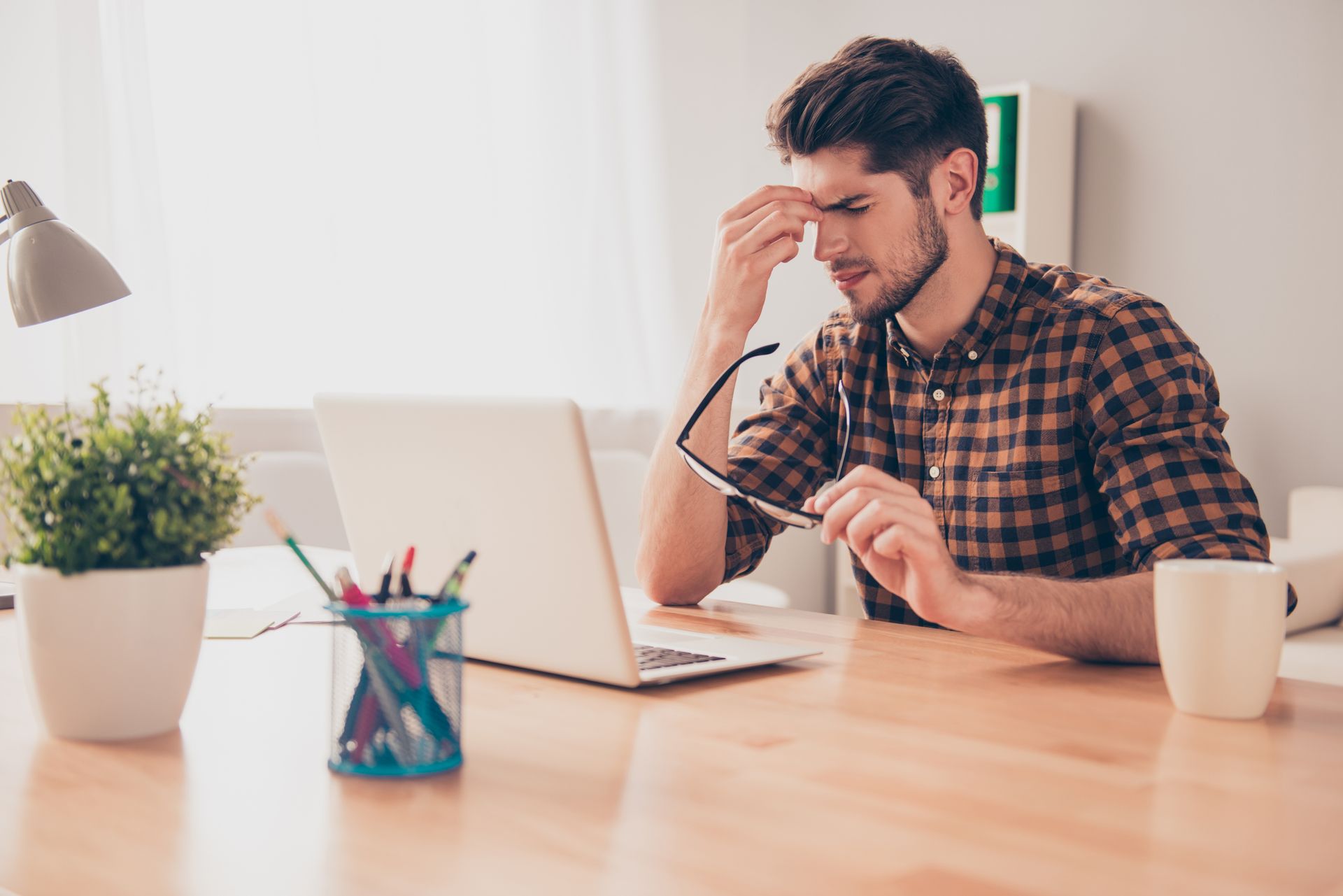 A man is sitting at a desk in front of a laptop computer.