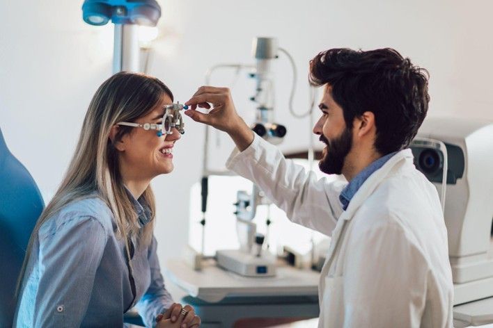 An optometrist is examining a woman 's eye with an examination tool.