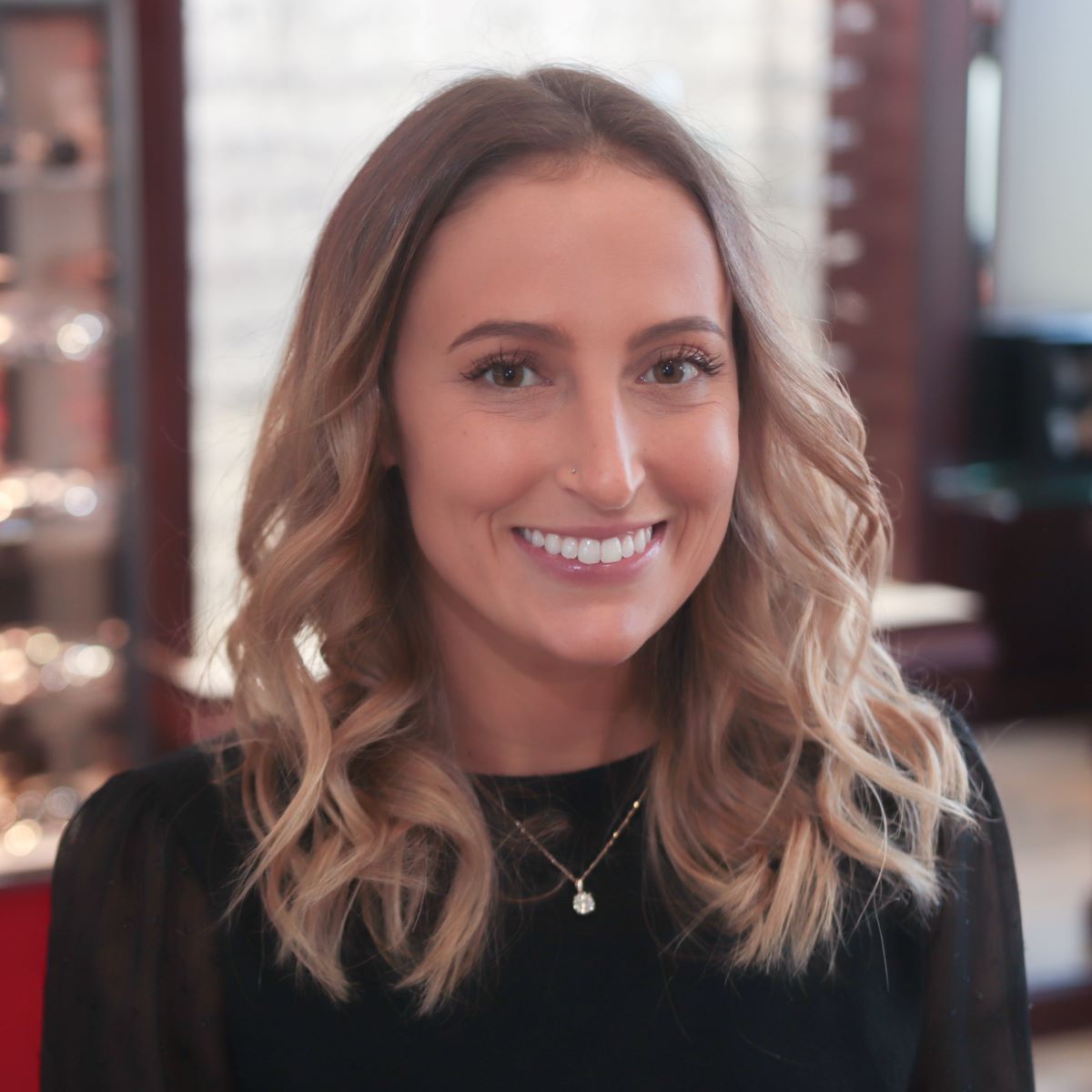 A woman wearing a black shirt and a necklace smiles for the camera