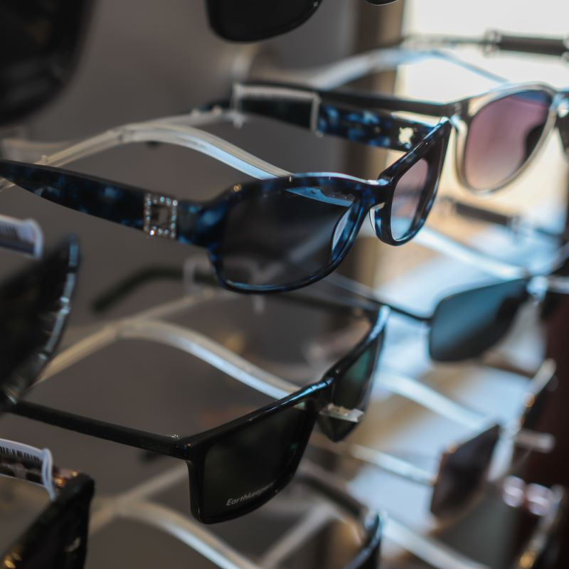 Several pairs of sunglasses are lined up on a rack