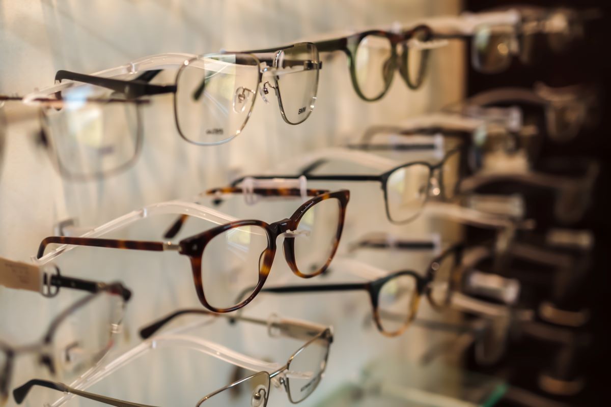 A row of glasses hanging on a rack in an optical shop.