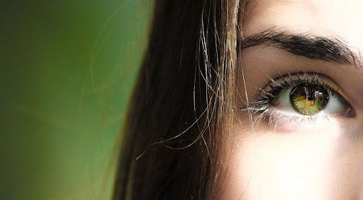 A close up of a woman 's green eye with long eyelashes.