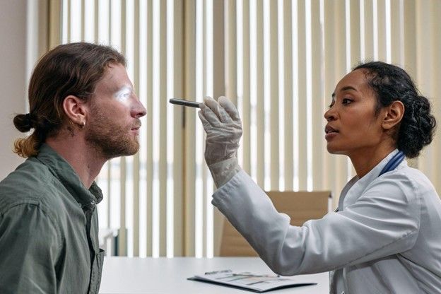 A doctor is examining a patient 's eye with a pen.