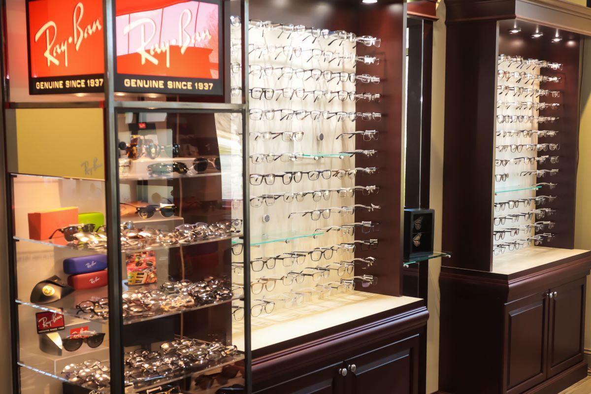 Sunglasses displayed in a retail eyewear shop, with illuminated wall racks and glass cases.