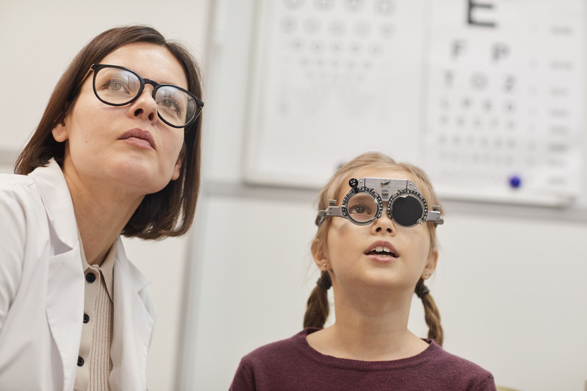 An ophthalmologist is examining a young girl 's eyes.