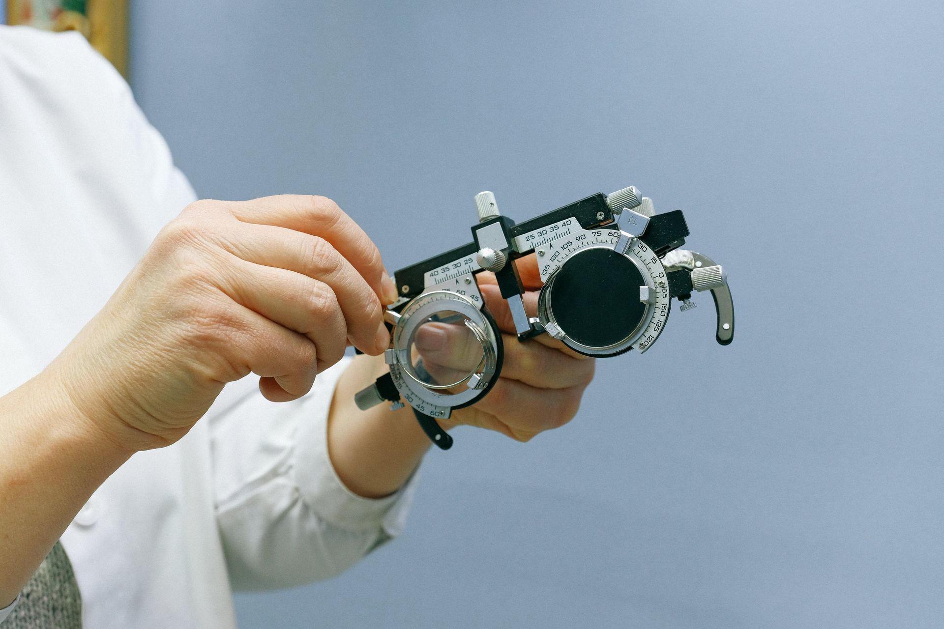 A person is holding a pair of glasses in their hands.