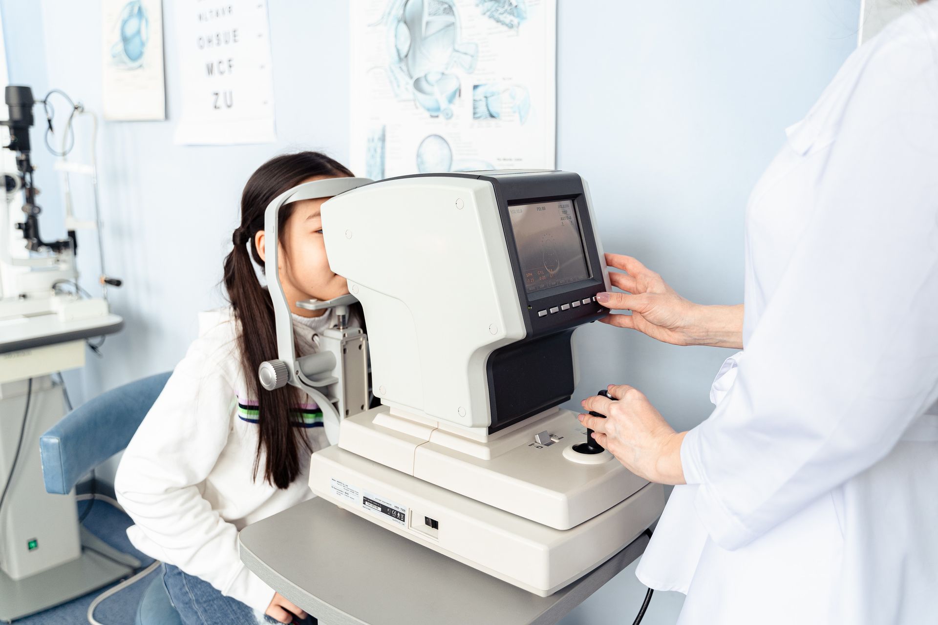 Patient undergoing an eye exam with an optometrist using an autorefractor in a bright clinic